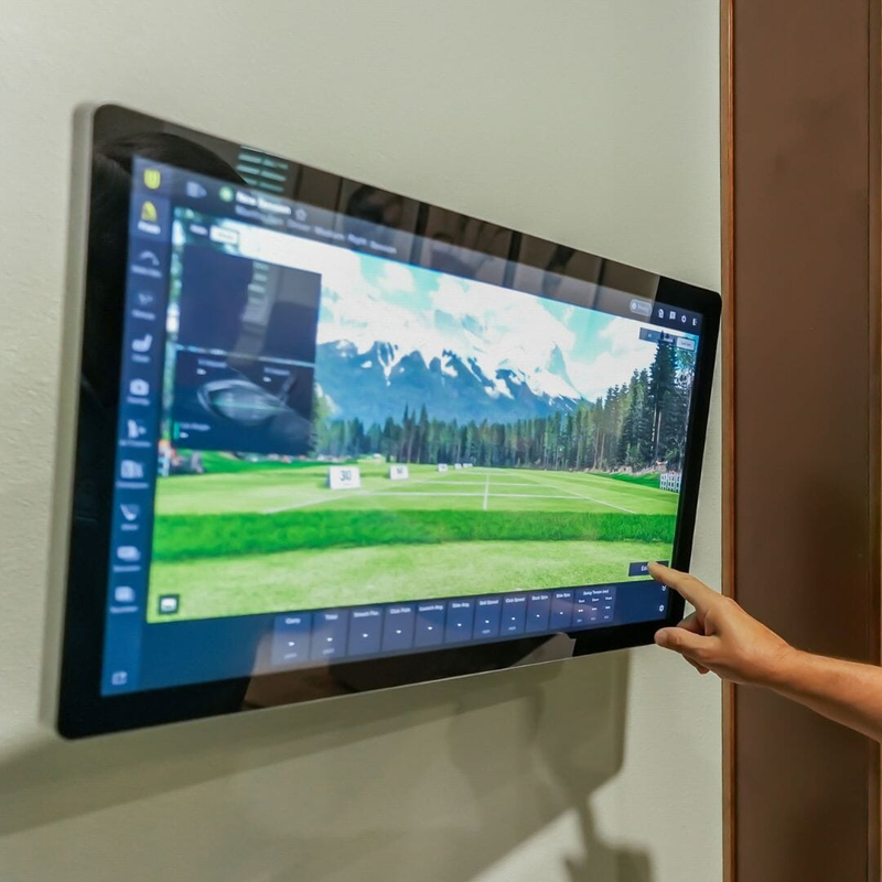 Hand using the touchscreen control on the 27 inch 4K golf simulator monitor.