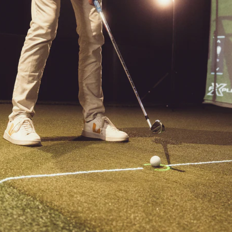 Foresight Sports Focus Club Tracer System person standing with club ready to hit golf ball on indoor turf.