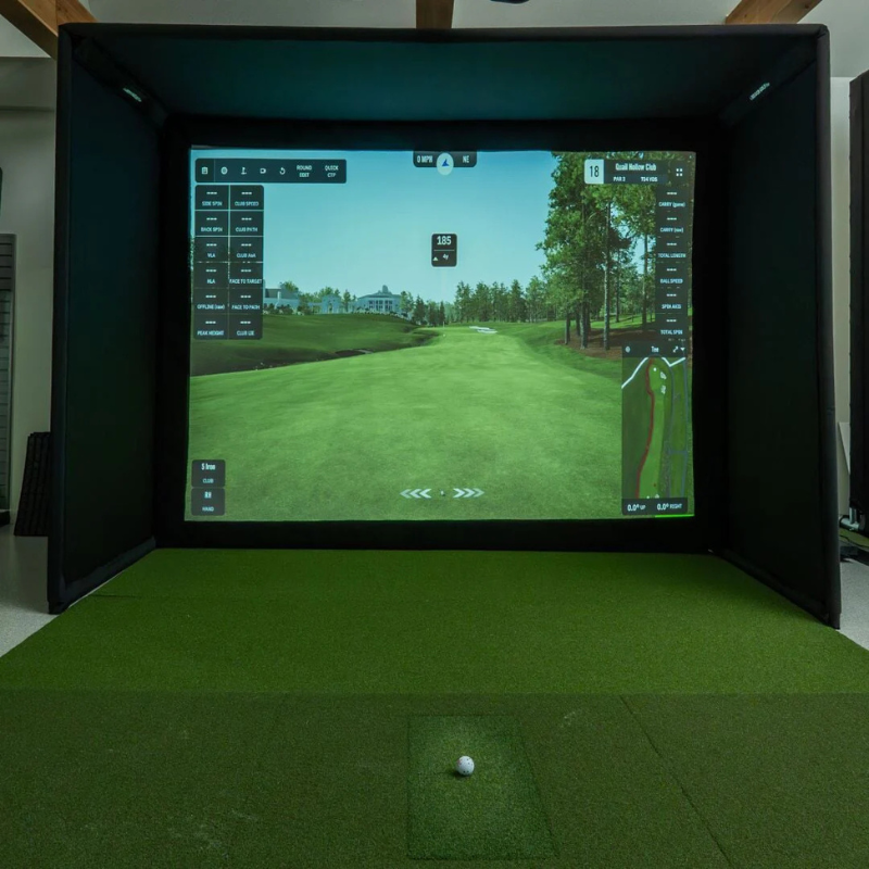 SIGPRO Premier Golf Simulator Impact Screen in a front view of a full simulator setup with digital course display and a ball on green turf.