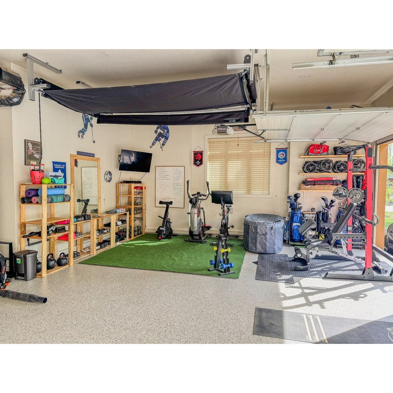 The SportsScreen Vanish Series Golf Simulator Enclosure retracted above a garage gym.