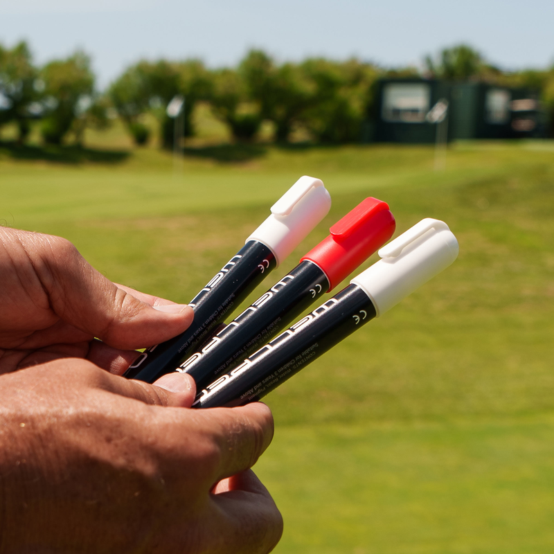 Golfer holding Wellpen chalk pens on the green.